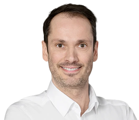 Bernhard Maier lächelt in die Kamera. Er trägt ein weißes Hemd mit offenem Kragen. Er hat kurzes, dunkelbraunes Haar und einen leichten Bartschatten.