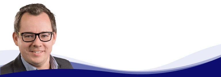 Dominik Fimberger, Bereichsleiter Marketing und E-Commerce bei Weyland Steiner, lächelt in die Kamera. Er trägt eine Brille mit dunklem Gestell, ein hellblaues Hemd mit offenem Kragen und ein graues Sakko darüber. Seine Haare sind kurz und braun und er trägt keinen Bart.