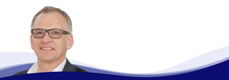 Wolfgang Maier, directeur marketing chez LEUCO, regarde aimablement la caméra. Il porte des lunettes noires marquées, une chemise blanche à col ouvert et une veste sombre. Ses cheveux courts sont grisonnants.