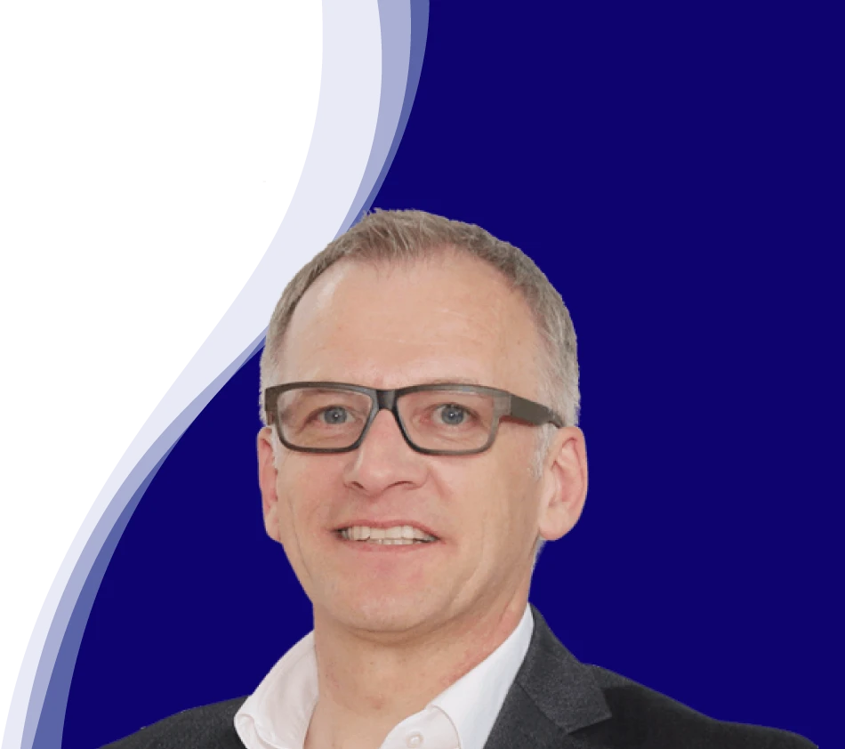 Wolfgang Maier, directeur marketing chez LEUCO, regarde aimablement la caméra. Il porte des lunettes noires marquées, une chemise blanche à col ouvert et une veste sombre. Ses cheveux courts sont grisonnants.